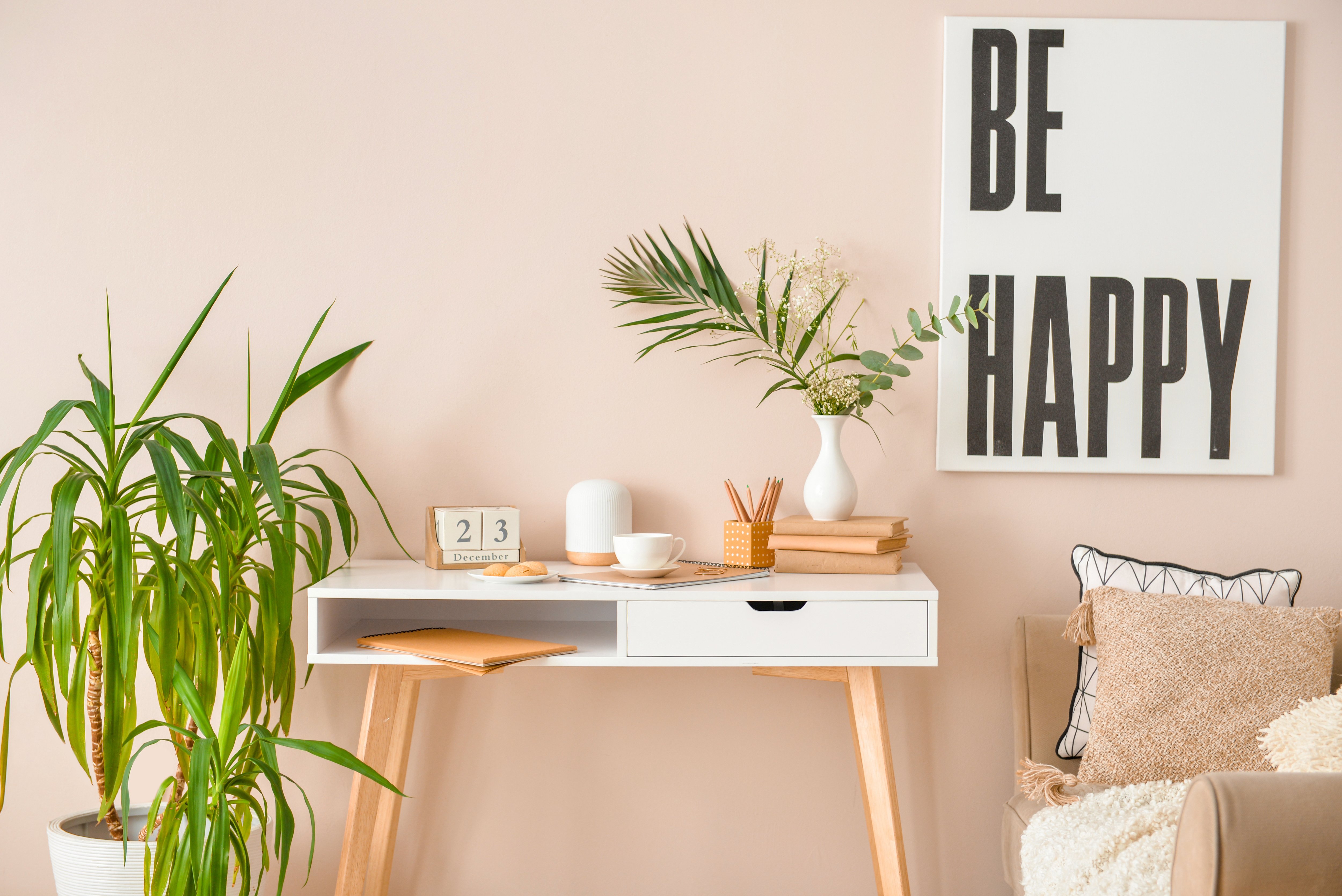 A modern, neutral office with plants and a white writer’s desk.